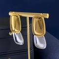 Detail view of rectangular titanium steel earrings in gold and silver on a jewelry stand - Silver