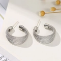 Detailed close-up of silver textured multi-layered hoop earrings on a minimalist background - Silver Stud Earring Style