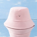 Pink cotton bucket hat featuring a black smiley face print on a light blue wood background - Printed Smiley Face Bucket Hat - Pink / One Size