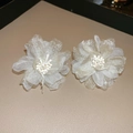 Detalle de pendientes de flores de organza crema con perlas sobre fondo de cuero fino - Estilo Flor / crema