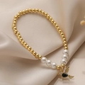 Elegante pulsera de perlas con cuentas doradas y colgante de pájaro con gema negra - Pájaro de Gota de Agua Negra