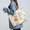 Beige canvas tote bag with rabbit illustration and brown straps, worn with denim jacket - Moon Rabbit - Beige