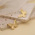 Elegante goldene Titanstahl Schmetterling Ohrstecker auf Steinrequisiten präsentiert - Gold