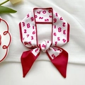 Elegant white silk-touch scarf with red numbers tied as a bow on a white fabric - Red Border Numbers