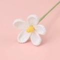 Close-up of handmade crochet daisy flower with white petals and yellow center on pink backdrop - White