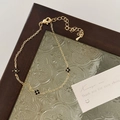 Detail of a gold-plated link bracelet with black clover motifs on textured glass - Clover Bracelet / Gold Black