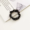 Elegant dark brown shimmering scrunchie with metallic fabric texture on an open book - Bronze Metallic