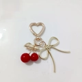 Gold cherry keychain with red fruit pendants and a golden bow on a decorative ceramic plate - Red Cherry Large Bow Gold Buckle (Cherry U)