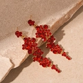 Dettaglio di orecchini con nappe in cristallo rosso con strass e finitura dorata - Orecchini pendenti con fiori di strass rossi e perno in argento sterling 925