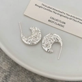 Macro detail of silver crescent earrings with a unique hammered lava texture finish - Textured Crescent / Silver