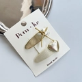 Golden bow and heart-shaped sequins hair clips on beige display card with a metal tray - Knotted Bow + Heart