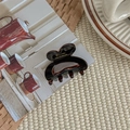 Close-up of a small heart-shaped tortoiseshell hair claw clip on an open magazine - Dark Coffee