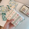 Detailed macro view of various floral cotton pouches with a simple wish woven label - Green Stripes with Rose Red Flowers