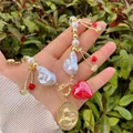 Detail of 18k gold heart cherry pendant necklace with baroque pearls and religious medal - Gold White