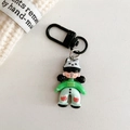 Detailed view of cartoon doll keychain with green sweater and black metal clasp - Black