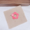 Macro shot of a pink flower hair clip on beige burlap with a soft white paper background - Watermelon red