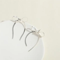 Detail of silver bow tassel earrings featuring long snake chain fringes on a stone tray - Medium-Short Style / Silver