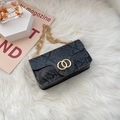 Black snakeskin textured crossbody bag with gold hardware on white fur background - Black