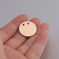 Primer plano de un colgante redondo de 21mm oro rosa con dos agujeros sobre una palma - 21mm / Oro rosa