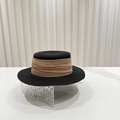 Close-up of black straw sun hat with elegant khaki pleated ribbon on rippled glass - Black