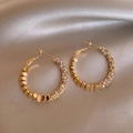 Macro detail of gold-plated hoop earrings with pavé crystals on champagne satin background - A1419 Gold Hammered Texture Hoop Earrings