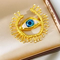 Dettaglio macro della spilla vintage dorata con occhio in resina blu e strass brillanti - Stile Malocchio Radiante Con Punte (Oro)