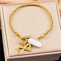 Pulsera dorada de acero con lazo, perla y circón cuadrado sobre caja de joyería - Dorado