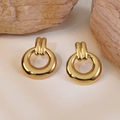 Polished gold geometric round drop earrings displayed on natural wooden stone pedestals - Gold