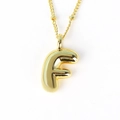 Close-up of golden bubble letter F pendant with a polished finish and thin chain necklace - Letter F