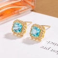 Elegant gold square stud earrings featuring a light blue gemstone with zircon halo - Blue