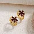 Macro view of gold flower earrings set with six deep red gemstones on textured background - Red (YH501)