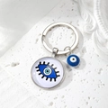 Detail of silver Evil Eye keychain with blue glass pendant on a white textured stone surface - 7# Black Eyelash Blue Eye