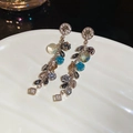 Detail von Vintage Quastenohrringen mit blauen Kristallperlen und goldenen Blattschmuck - Silberner Ohrstecker - Grau / Grau