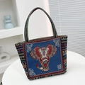 Ethnic style tote bag featuring blue canvas with colorful elephant embroidery and striped handles - Blue Front Elephant