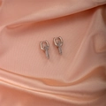 Nahaufnahme der silbernen U-Ohrringe mit Zirkon-Anhängern auf rosa Seidenhintergrund - Pavé Ovales Glied / Silber