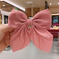 Elegant large red and white gingham bow hair clip with trailing ribbons in hand - Gingham / Burgundy