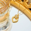 Macro di una collana a cuore dorata con micro-pavé di zirconi su superficie a specchio - Collana Oro