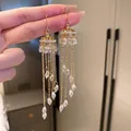 Detailed close-up of golden tassel earrings featuring delicate crystal water-drop pendants - Gold