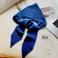Vista detallada de una bufanda con capucha de punto azul sobre una sábana blanca - Juego integrado de gorro y chal / Azul