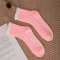 Detail showing pink coral fleece socks with white cuffs and non-slip grippers on brown felt - One Size / Bright Pink with Grippers