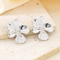 Macro shot of silver floral earrings with pearl centers on beige silk fabric - Silver Blooming Flower (KE113881-KFC)