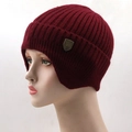 Close-up of wine red ribbed knit beanie with ear flaps and metallic shield logo - Burgundy