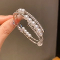Detailansicht eines mehrlagigen Spiralarmreifs mit Perlen und Kristallen an der Hand - 26# Armband-Silber