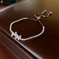 Macro detail of zircon butterfly bracelet with adjustable bolo clasp on leather background - Silver
