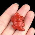 Mini red agate turtle gemstone carving held in hand with natural black textures - Red Jasper