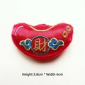 Close-up of red satin gold ingot charm with gold Cai embroidery and blue clouds - Sycee / Ingot