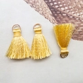 Close-up of three golden fabric tassels with gold metal rings for DIY jewelry making - Bronze