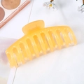 Detailed close-up of a translucent yellow keel hair claw clip on a white fabric background - Jelly Orange