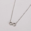 Dettaglio di un ciondolo a simbolo infinito con zirconi incastonati su una catena sottile - Collana Argento