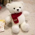 Weißer Teddybär-Plüsch mit rotem Strickschal und Smile-Label auf weichem beigem Teppich - Weißer Schal-Stil